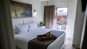A neatly made bed with a tray of toiletries, a nightstand with a lamp, and a view of the outdoors through a sliding door.