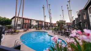 A swimming pool surrounded by palm trees and outdoor seating areas. - 205 Fully Furnished 1BR Suite-Prime Location! by RedAwning (Scottsdale)