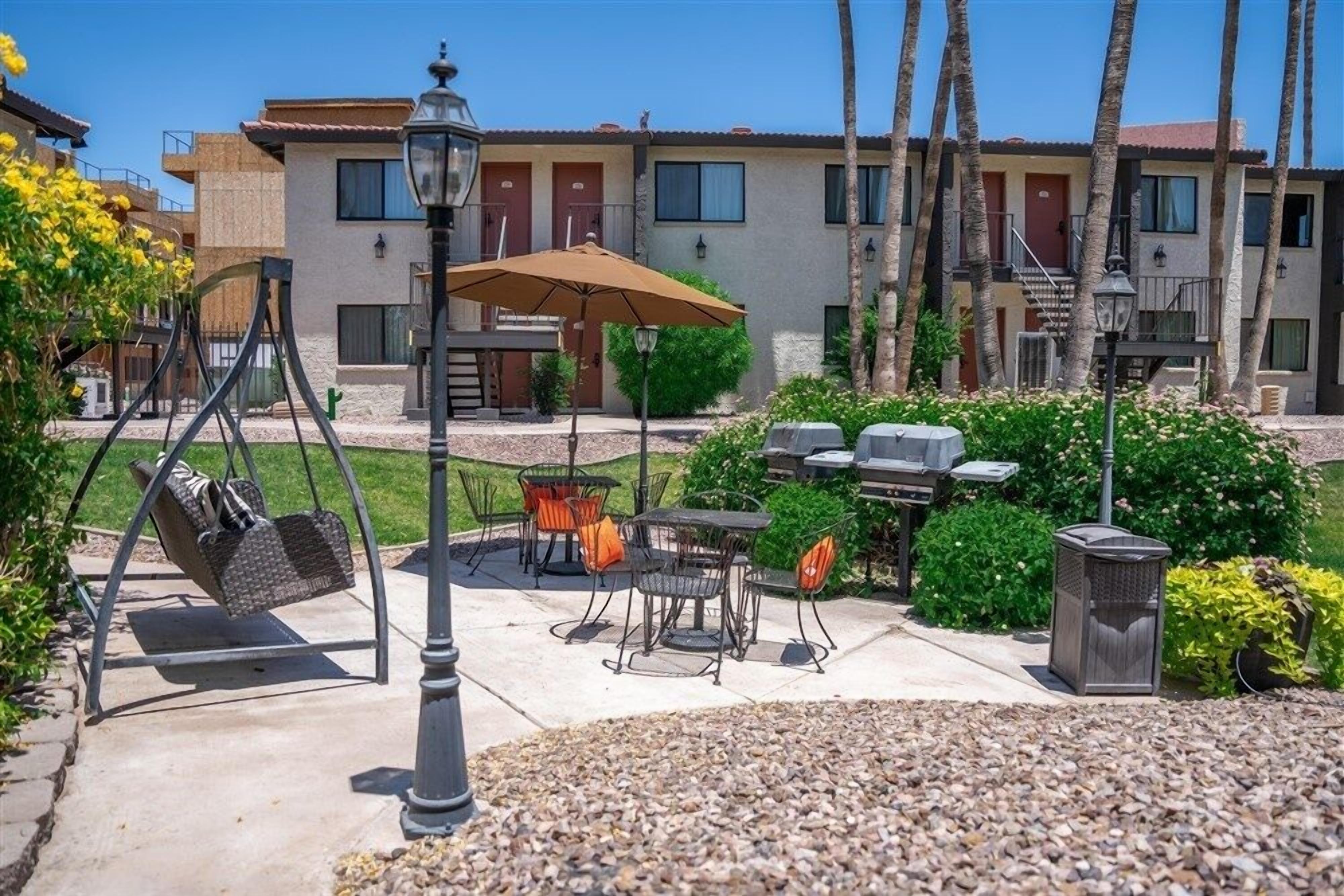 A patio area with outdoor furniture, a swing set, and a barbecue grill.
