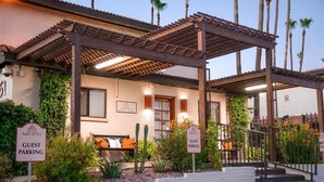 A building with a guest parking sign, a covered entrance with a pergola, and a bench outside. - 205 Fully Furnished 1BR Suite-Prime Location! by RedAwning (Scottsdale)