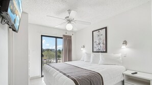 A bedroom with a bed, a ceiling fan, a TV, a nightstand, a lamp, and a painting. - 244 Fully Furnished 1BR Suite-Pet Friendly! by RedAwning (Scottsdale)
