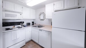A modern kitchen with white cabinetry, a microwave, stove, sink, and dishwasher. - Scottsdale's premium short term getaway, Fully furnished 1 bedroom homes, FREE Golf, cable, utilities, Wi-Fi, parking, pool, and bike trails- Unit 241 by RedAwning (Scottsdale)
