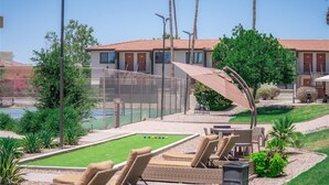 A pool area with lounge chairs, a table, and a small garden. - Scottsdale's premium short term getaway, Fully furnished 1 bedroom homes, FREE Golf, cable, utilities, Wi-Fi, parking, pool, and bike trails- Unit 241 by RedAwning (Scottsdale)