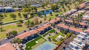 Un quartier résidentiel composé de plusieurs immeubles à deux étages, d’un court de tennis et d’un petit lac.