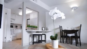 A modern kitchen with white cabinets, a welcome sign, and a dining area with a round table and chairs. - 202 Fully Furnished with WiFi by RedAwning (Scottsdale)