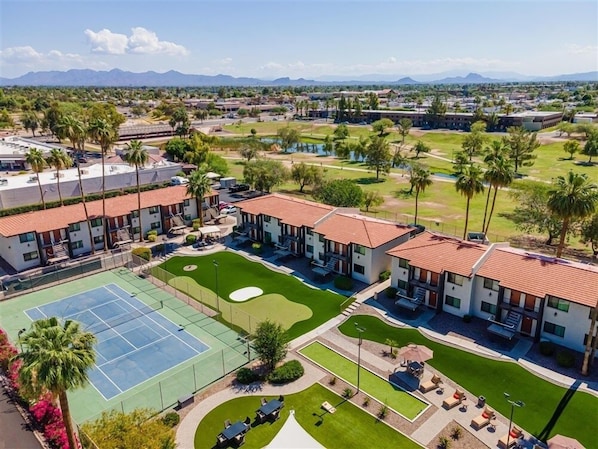 A hotel with multiple buildings, a tennis court, and a golf course.