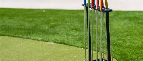 A croquet set on artificial grass with a metal stand.