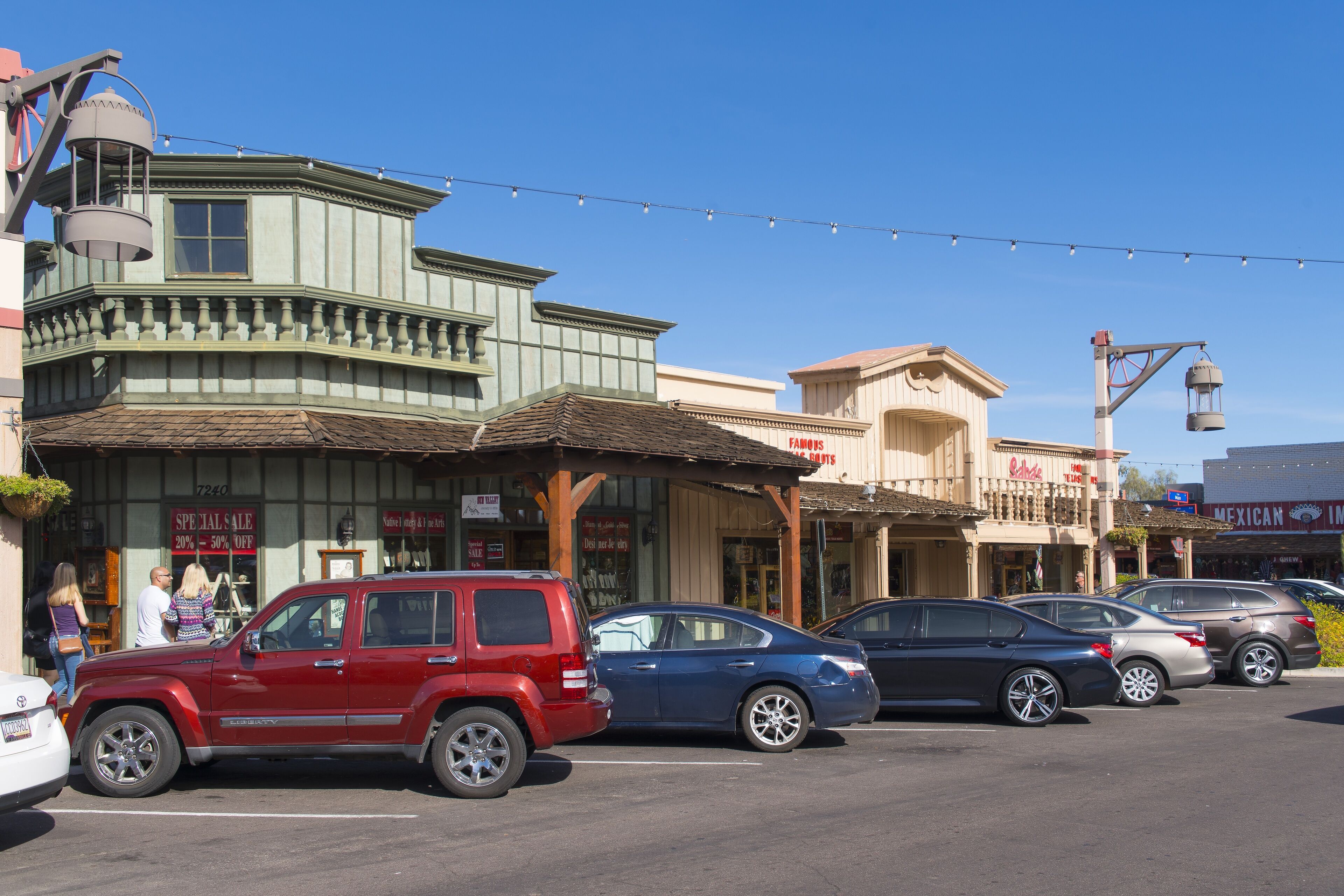 A street with parked cars and buildings with signs, including one that says "FAMOUS."