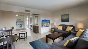 Ein modernes Wohnzimmer mit Sofa, Couchtisch und Wand-Fernseher.