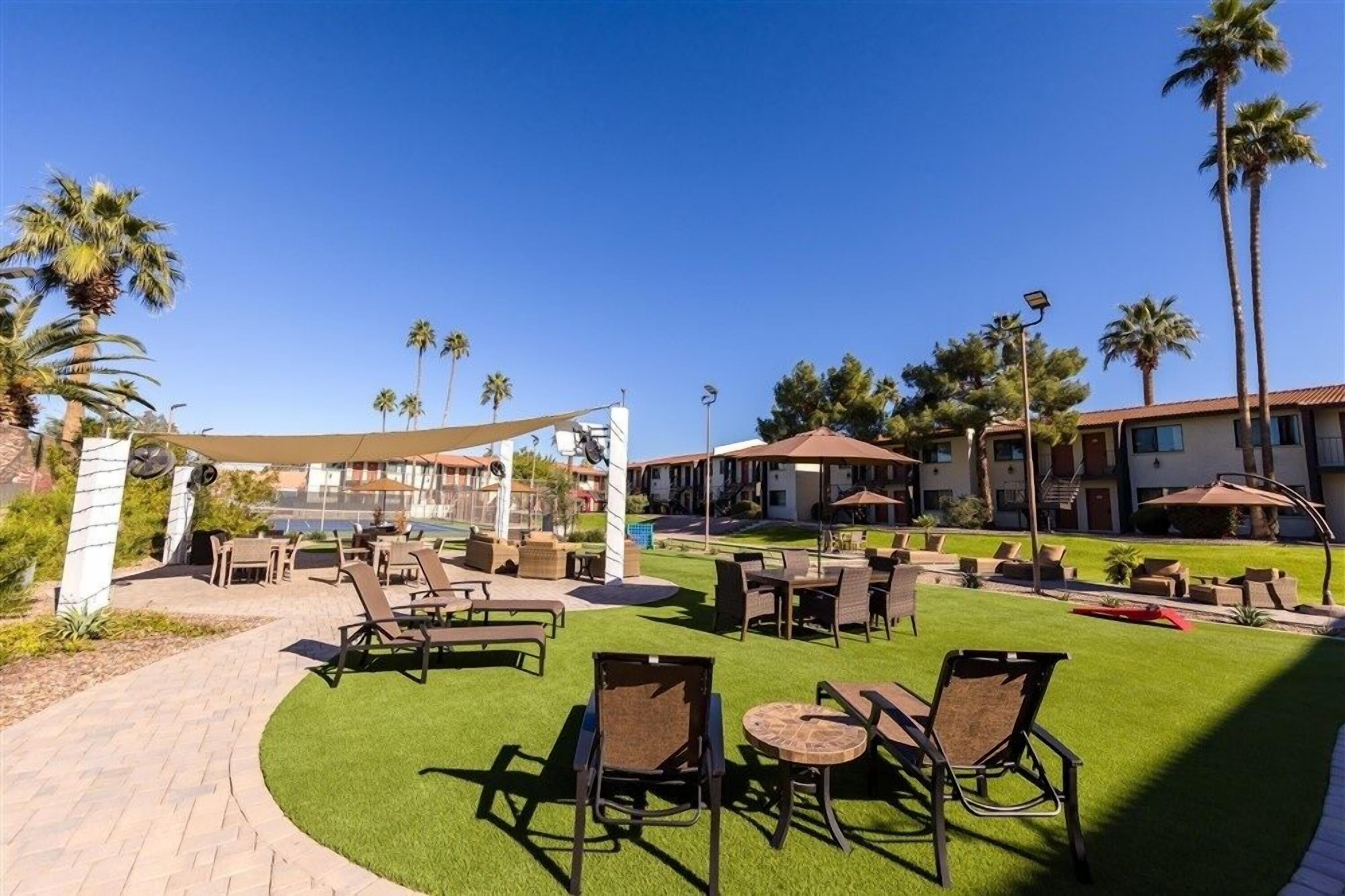 A resort with outdoor seating, palm trees, and a pool.