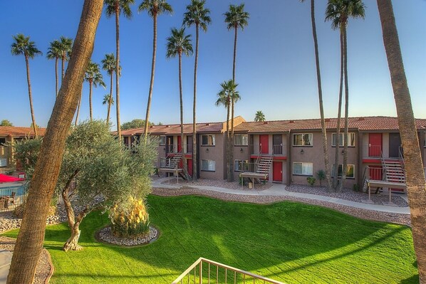 A hotel with multiple-story buildings, palm trees, and a well-maintained lawn.