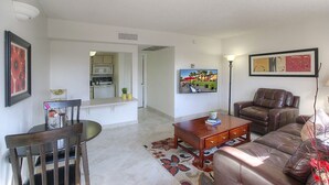 A living room with a brown leather sofa, a wooden coffee table, and a dining table with chairs. There is a kitchen in the background with a microwave and cabinets. - 116 Fully Furnished 1BR Suite-Prime Location! by RedAwning (Scottsdale)