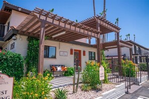 Guests can relax on the covered patio, featuring a pergola and a bench with cushions.
