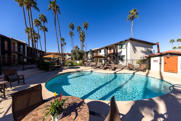 Relax by the pool surrounded by lounge chairs and umbrellas, with comfortable balconies nearby.