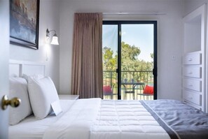 Relax in this serene space with a large bed, a painting above, and a sliding door leading to an outdoor area with a table and chairs.