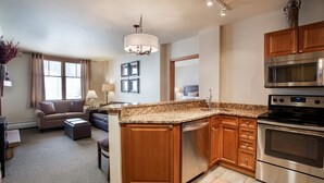 A modern kitchen with granite countertops, stainless steel appliances, wooden cabinets, and a built-in dishwasher. - Zephyr Mountain Lodge, Condo | Ski-In/Ski-Out Continental Divide Views (Value-Rated Condo 2202) (Winter Park)