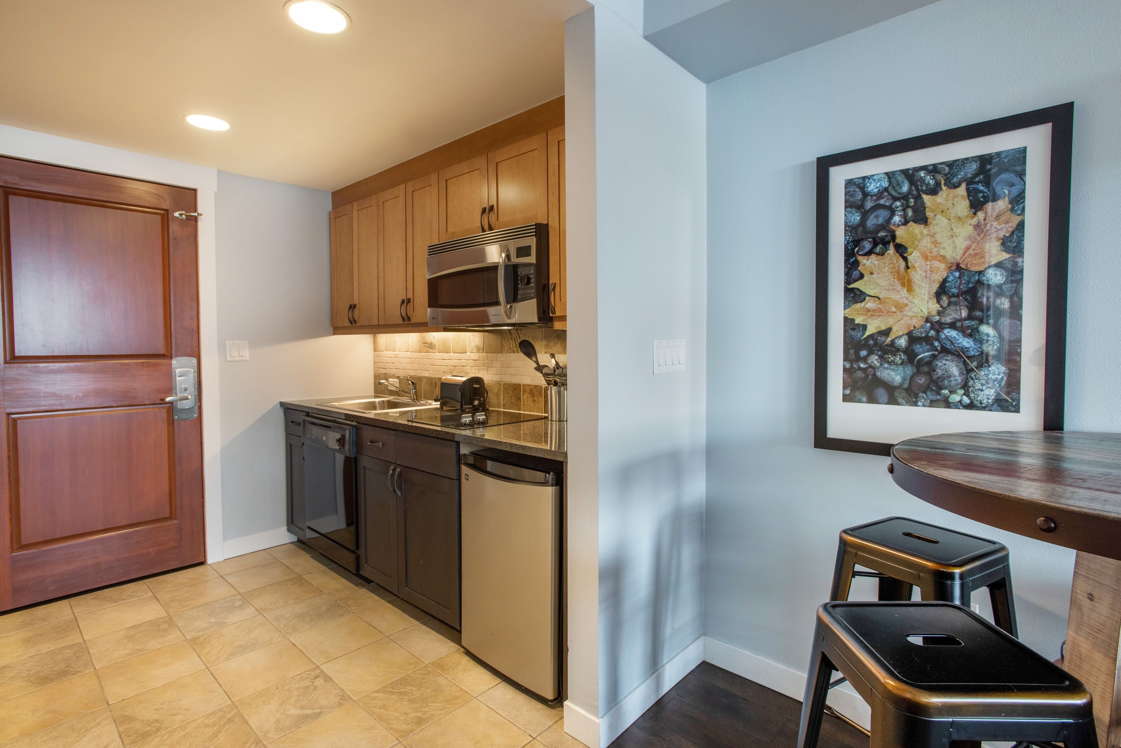 A kitchen with wooden cabinets, stainless steel appliances, and a tiled floor.