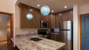 A kitchen with granite countertops, stainless steel appliances, and wooden cabinets. - Zephyr Mountain Lodge, Condo | 2 bedroom, Gas Fireplace & Continental Divide Views (Premium Rated Condo 1701) (Winter Park)