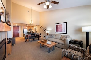 A spacious living room with a sofa, coffee table, and a dining area with chairs and a table.