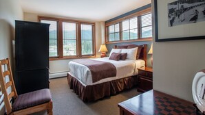 Une chambre d’hôtel avec un lit, un bureau, une chaise et un téléviseur.