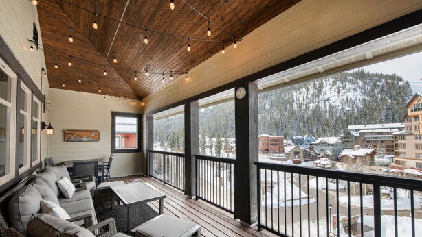 A covered outdoor area with a wooden ceiling, string lights, a sofa, and a view of a snowy mountain town. - Fraser Crossing/Founders Pointe, Condo | 3 bedroom Ski Slope Views (Select Rated Condo 3625) (Winter Park)