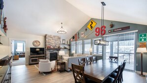A modern living room with a dining area, fireplace, and large windows. - Fraser Crossing/Founders Pointe, Condo | 3 bedroom Ski Slope Views (Select Rated Condo 3625) (Winter Park)