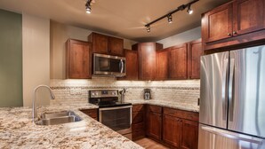 A kitchen with wooden cabinets, stainless steel appliances, and a granite countertop. - Zephyr Mountain Lodge, Condo | 1 Bedroom - (Premium-Rated Condo 2319) (Winter Park)