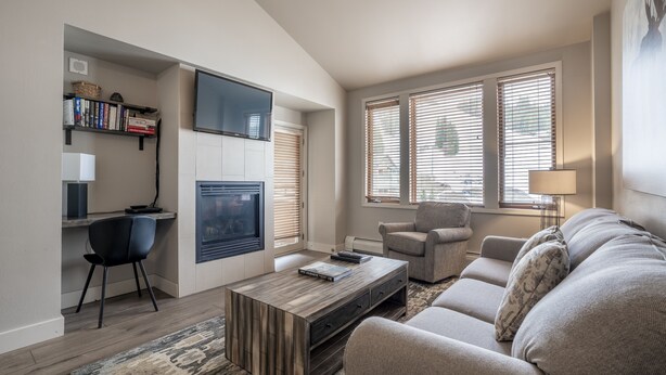 A modern living room with a sofa, a coffee table, a TV, and a bookshelf. - Zephyr Mountain Lodge, Condo | 1 Bedroom - (Premium-Rated Condo 2319) (Winter Park)