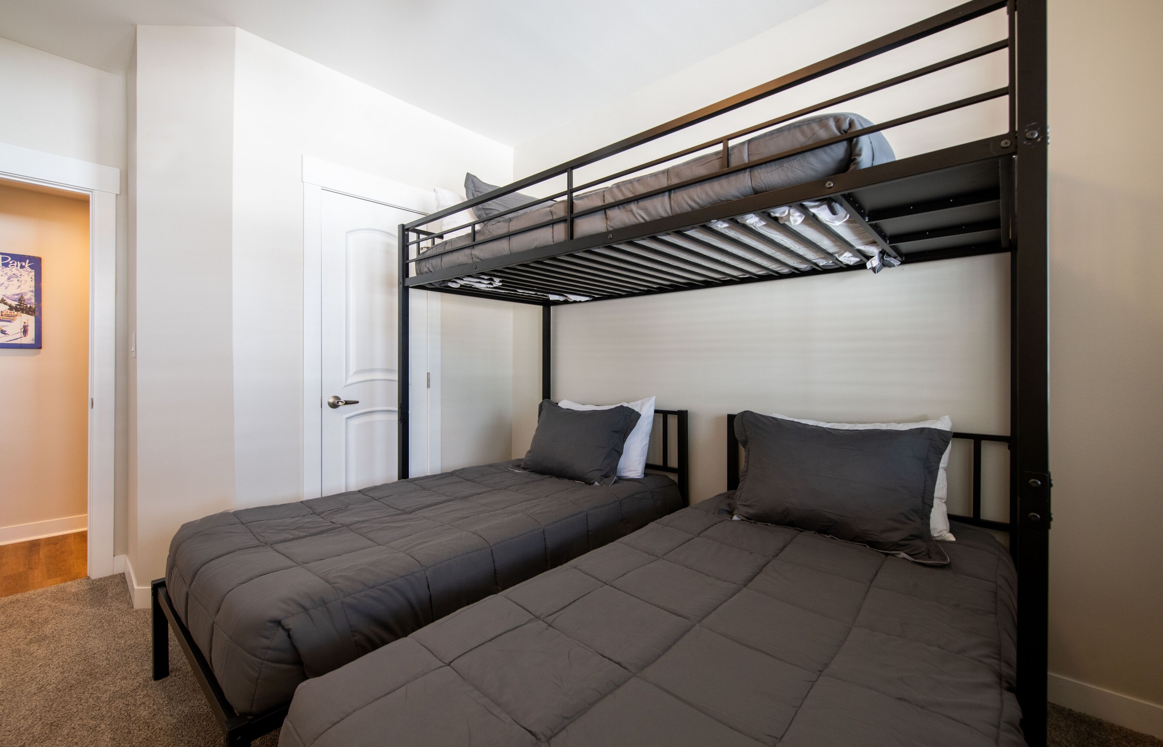 A bunk bed room with two single beds, a door, and a poster on the wall.