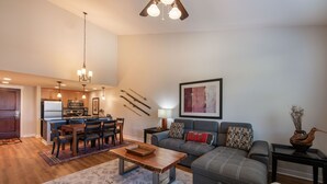 A spacious living room with a gray sofa, a wooden coffee table, and a dining area with a kitchen in the background. - Fraser Crossing/Founders Pointe, Condo , Gondola Access (Select-Rated Condo 4654) (Winter Park)