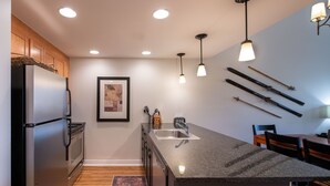 A modern kitchen with a granite countertop, stainless steel appliances, and pendant lighting. - Fraser Crossing/Founders Pointe, Condo , Gondola Access (Select-Rated Condo 4654) (Winter Park)