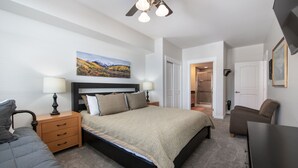 A bedroom with a bed, bedside tables, a ceiling fan, a painting, and a door leading to another room. - Fraser Crossing/Founders Pointe, Condo , Gondola Access (Select-Rated Condo 4654) (Winter Park)