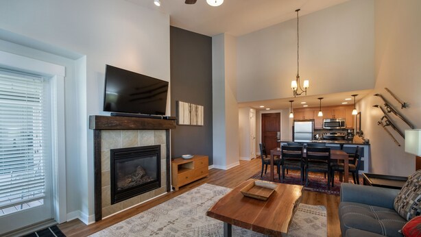 A spacious living room with a fireplace, a television, and a dining area with a kitchen in the background. - Fraser Crossing/Founders Pointe, Condo , Gondola Access (Select-Rated Condo 4654) (Winter Park)