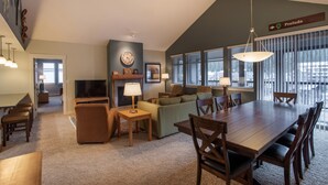 A spacious living room with a large wooden dining table, comfortable seating, a fireplace, and a television. - Fraser Crossing/Founders Pointe, Condo | 2 Bedroom (Value-Rated Condo 3426) (Winter Park)