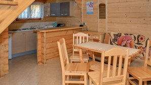 Een houten hut met een keukenhoek, eettafel en stoelen.