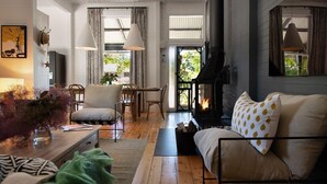 A cozy living room with a fireplace, wooden furniture, and a view of the outdoors. - The Elm Tree- Designer Home in the heart of Daylesford (Daylesford)