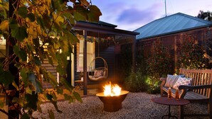 A cozy outdoor seating area with a fire pit, a hanging chair, and a bench. - The Elm Tree- Designer Home in the heart of Daylesford (Daylesford)