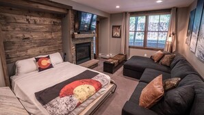 Ein Schlafzimmer mit Bett, Kamin, Sofa und Fernseher.