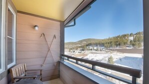 Ein Balkon mit einer Holzbank und einem Ski Stock, der an der Wand lehnt.