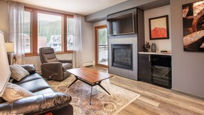 Ein modernes Wohnzimmer mit Ledersofa, Relaxsessel, Couchtisch aus Holz und Kamin.