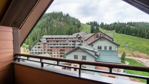 A view of a hotel with multiple buildings, a green lawn, and a forested hillside. - Zephyr Mountain Lodge, Condo | 2 Bedroom (Select-Rated Condo 1415) (Winter Park)