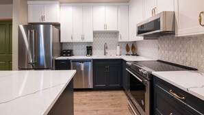 A modern kitchen with stainless steel appliances, white cabinetry, and a patterned backsplash. - Zephyr Mountain Lodge, Condo , 3 Bedroom (Premium-Rated Condo 2505) (Winter Park)