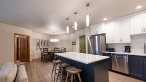 A modern kitchen with a central island, stainless steel appliances, and wooden bar stools. - Zephyr Mountain Lodge, Condo , 3 Bedroom (Premium-Rated Condo 2505) (Winter Park)