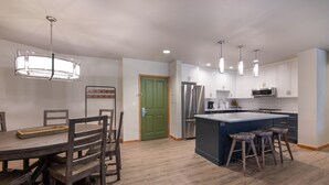 A modern kitchen with a central island, wooden chairs, and a dining table. - Zephyr Mountain Lodge, Condo , 3 Bedroom (Premium-Rated Condo 2505) (Winter Park)