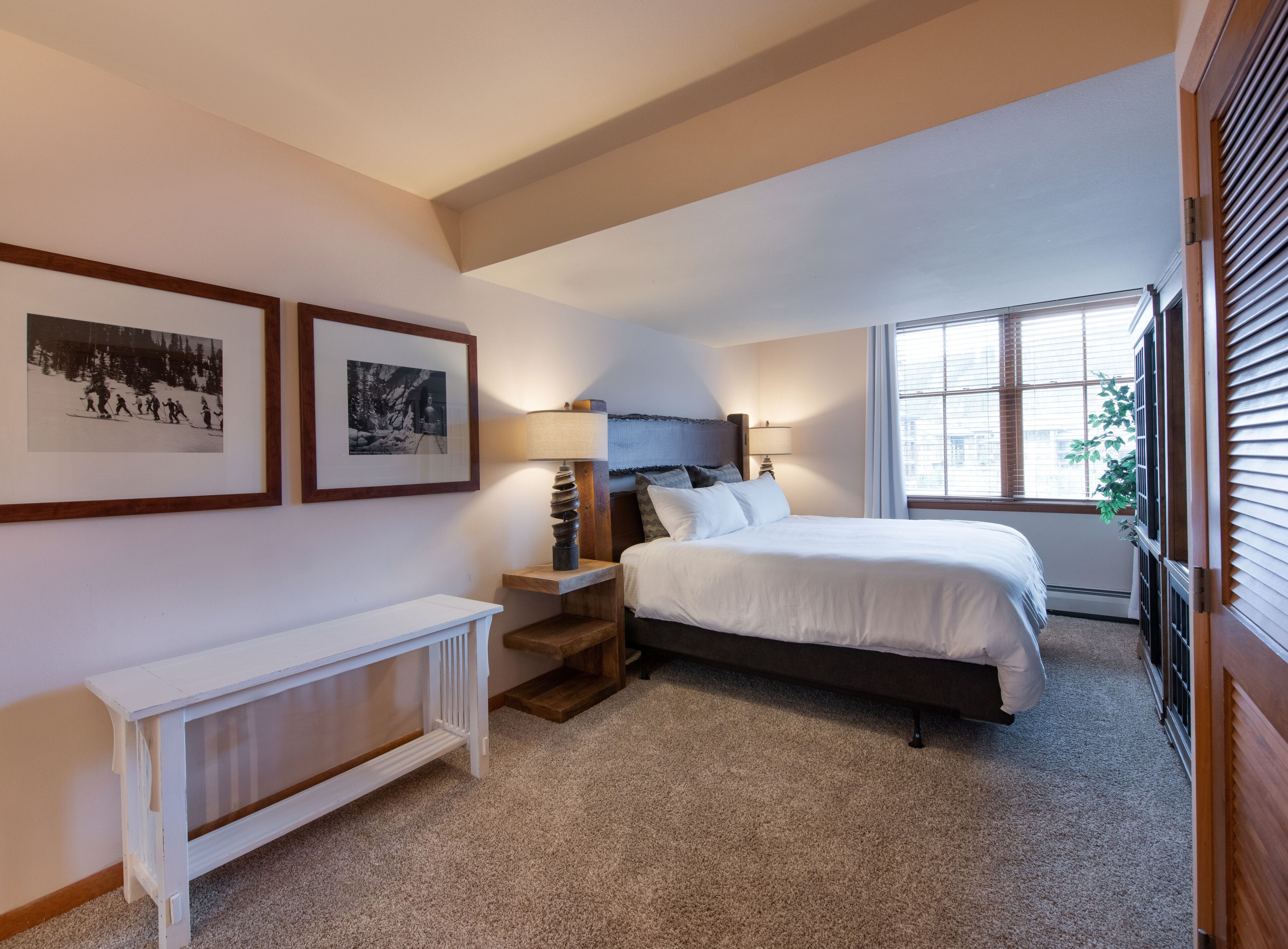 A bedroom with a bed, bedside tables, a radiator, and two framed pictures on the wall.