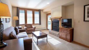 A living room with a sofa, armchair, coffee table, fireplace, television, and a lamp. - Zephyr Mountain Lodge, Condo | Ski Slope View (Select-Rated Condo 2405) (Winter Park)