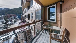 Un balcon avec vue sur une montagne enneigée, une chaise en bois et une table.
