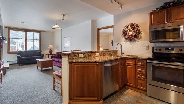 A modern kitchen with granite countertops, stainless steel appliances, and wooden cabinetry. - Zephyr Mountain Lodge, Condo | Ski-In/Ski-Out w/ Balcony Views (Value-Rated Condo 1516) (Winter Park)