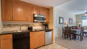 A kitchen with wooden cabinets, a stainless steel microwave, a dishwasher, and a coffee maker. - Fraser Crossing/Founders Pointe, Condo | Gondola Access (Premium-Rated Condo 3624) (Winter Park)