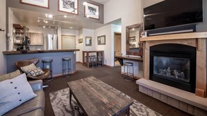 A spacious living room with a fireplace, a large TV, and a bar area. - Zephyr Mountain Lodge, Condo | Ski Storage (Select-Rated Condo 2700) (Winter Park)